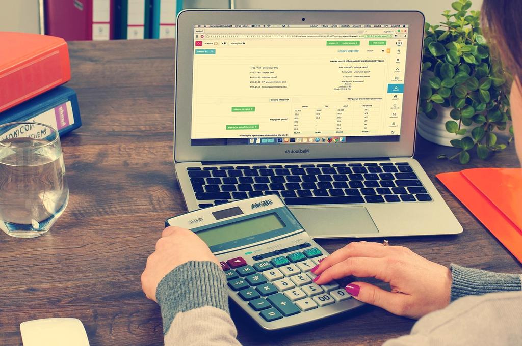 Person using a calculator on a wooden desk